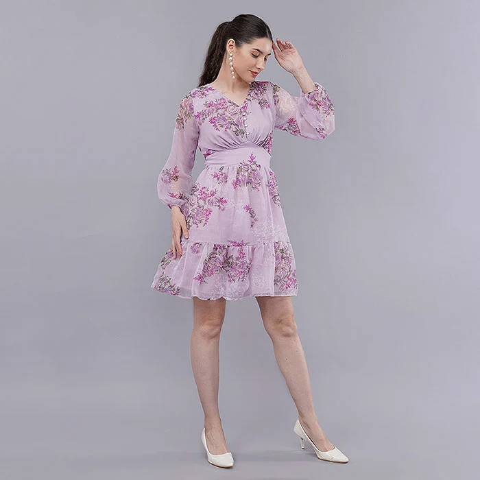 Colour accurate garment photography of an Indian female model in a lilac floral chiffon dress with balloon sleeves and a ruffled hem, posed on a soft grey seamless backdrop under even studio softbox lighting that keeps the pastel print true to life