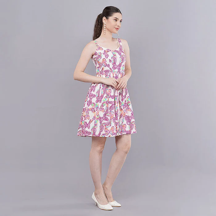 Full-length on-model catalogue photo of an Indian model in a pink paisley print sleeveless fit-and-flare dress on a soft grey studio backdrop, hand on hip, showing how a clean studio pose reveals garment length and silhouette for plus size model photography planning
