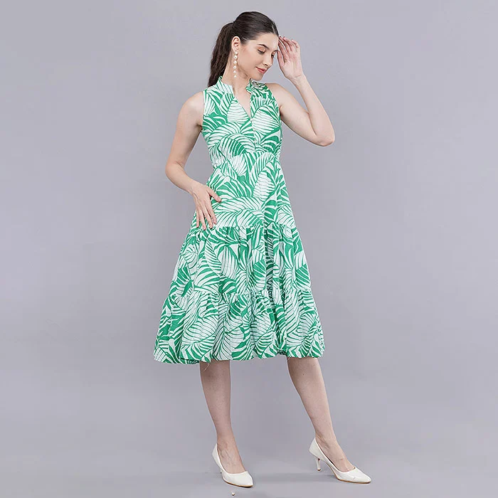Full-length studio photo of an Indian female model in a green and white palm print sleeveless tiered midi dress and white heels on a soft grey seamless backdrop, true-colour on-model catalogue image that sets clear expectations and helps reduce Meesho returns