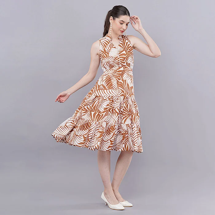 Meesho model photoshoot example of a young Indian woman in a sleeveless rust and cream tropical-leaf print fit-and-flare dress, mid-step pose with white heels against a light grey studio backdrop, soft even fashion lighting