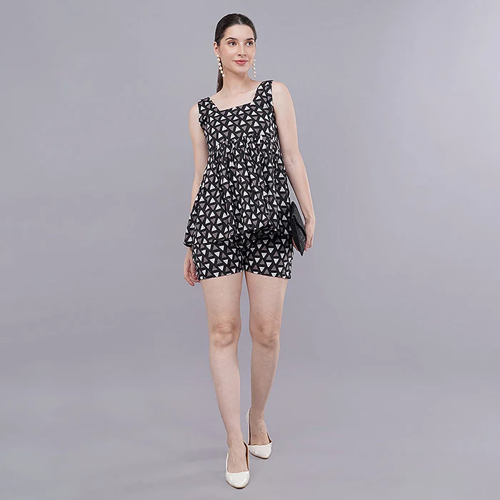 Indian female model in a black and white printed sleeveless playsuit with a black clutch and white heels, full-length front pose on a light grey seamless studio backdrop with soft even lighting, a clear thumbnail-friendly image for Myntra product listing ads