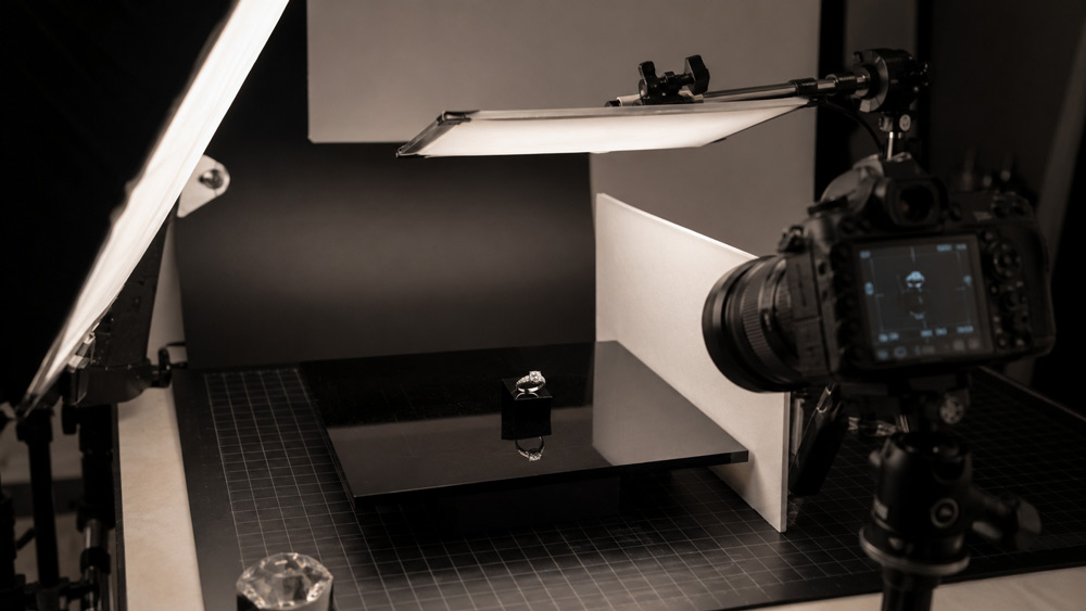 Professional jewellery photography studio in Delhi NCR showing tethered camera setup, softbox lighting and macro capture of gold pieces on black acrylic