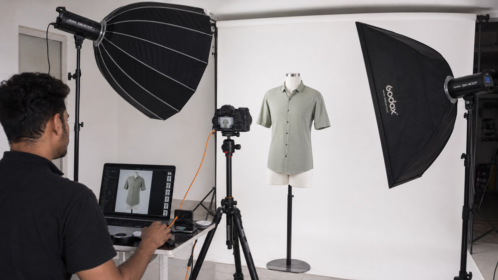 Behind the scenes apparel product photography studio setup at Uniqs Studio Delhi NCR with tethered capture, softbox lighting and clothing SKU on ghost mannequin form on white cyclorama