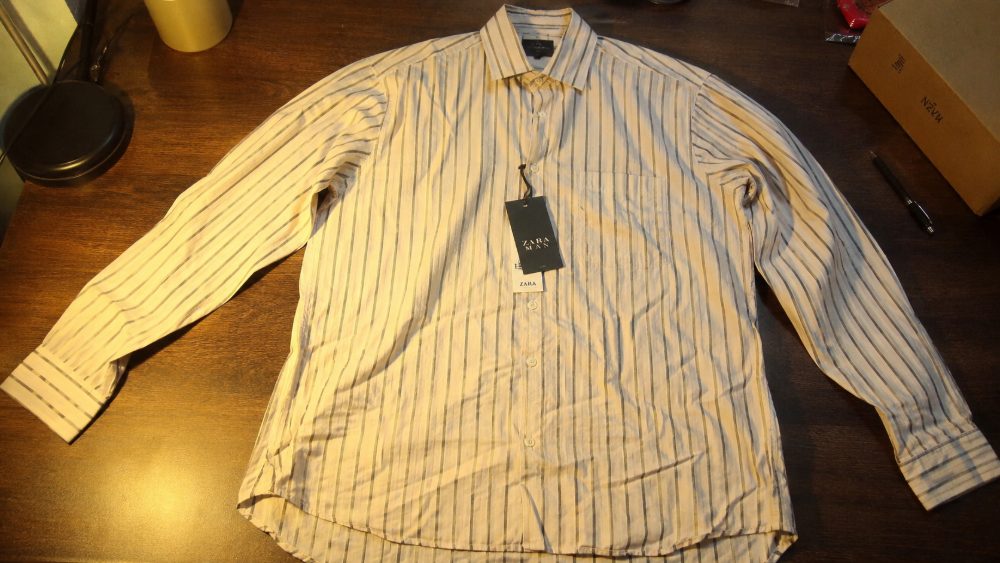 Behind the scenes of unprofessional clothing product photography example showing wrinkled cotton shirt with uneven yellow
