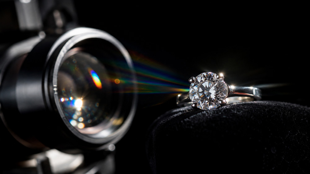 Ultra-cinematic hero banner of a luxury gold and diamond necklace on dark velvet surface with dramatic side lighting, macro focus, sparkles catching light, moody warm ambient background of a professional videography studio, editorial fashion magazine aesthetic — jewellery videos for Instagram by Uniqs Studio