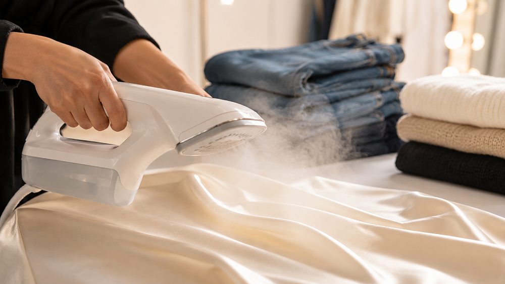 Behind the scenes of garment steaming guide for fashion photography showing a handheld steamer releasing soft steam across