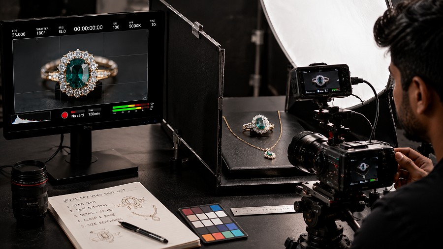 High-end jewellery ecommerce macro videography setup showing a gemstone ring and delicate necklace under controlled diffused lighting, macro camera focused on precise stone facets, metal reflections, clasp detail and true product scale, black flags and soft reflectors shaping highlights with a colour-accurate preview monitor, indian standard ecommerce photography & videography studio