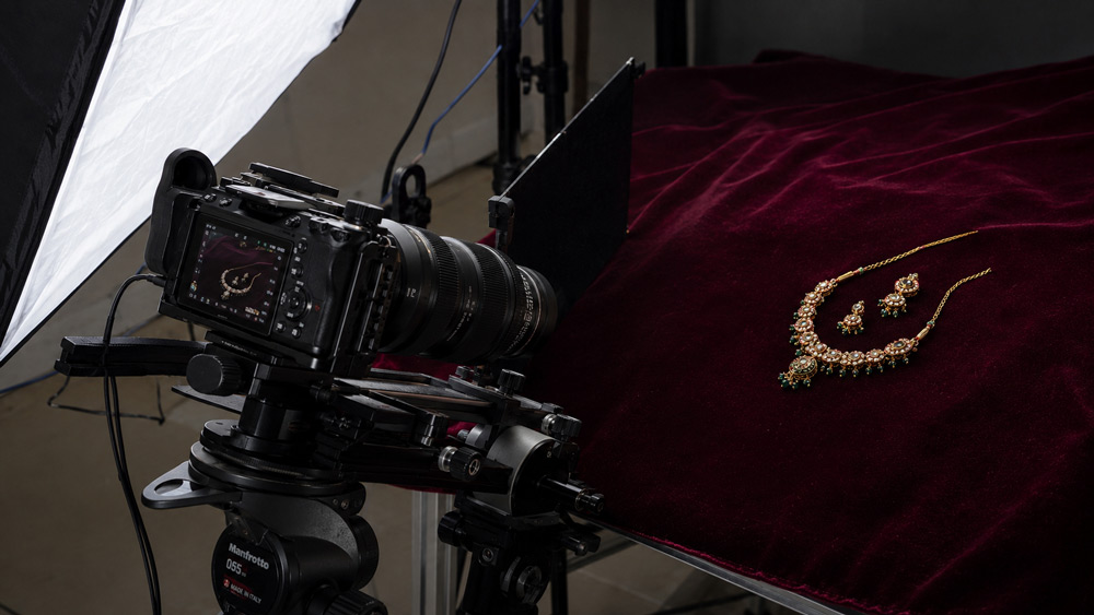 Ultra-detailed macro photography of traditional Indian Kundan bridal jewellery showing intricate meenakari enamel work in red green and gold on deep maroon velvet background — Uniqs Studio Delhi NCR